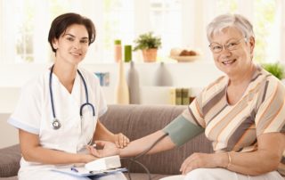 Nurse measuring blood pressure of senior woman at home.